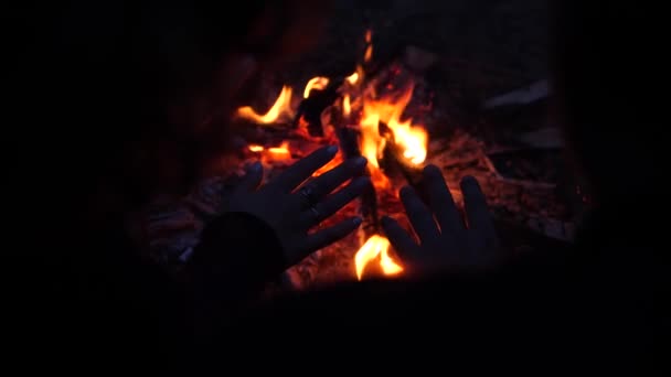 一个男人和一个女人在火边取暖他们的手掌 — 图库视频影像