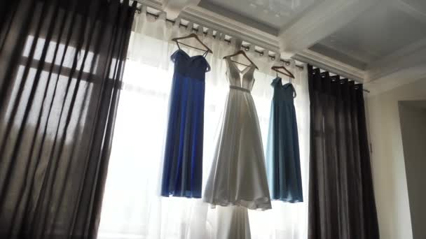 Bridesmaid dress and bridesmaid dresses hang on the window — Stock Video