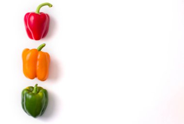 Çok renkli dolmalık biberler izole edilmiş beyaz arka planda yatar. Kırmızı biber, turuncu, sarı ve yeşil dolma biber. Düz yat, üst görüş, maket yap. Metin için alanı kopyala.