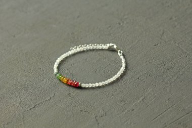 Doğal taşlardan yapılmış parlak bir bilezik. Çok renkli turmalin, ay taşı. El yapımı mücevherler. Karanlık modern arka planda el yapımı bilezikler..