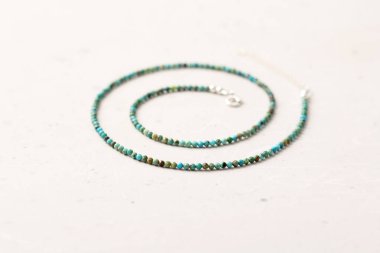Kısa bir kolye ya da doğal turkuazdan yapılmış boncuklar ve 925 gümüş. El yapımı mücevherler. Kolye boncukları hafif modern bir arkaplanda el yapımı..