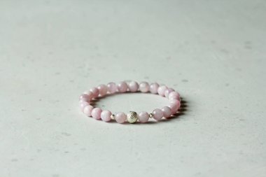 Kunzite bileziği. Bileklik, eldeki taşlardan yapılmış doğal bir kunzite taşından. Doğal taşlardan yapılmış bilezik. El yapımı mücevherler. Hafif modern arkaplanda el yapımı bilezikler.