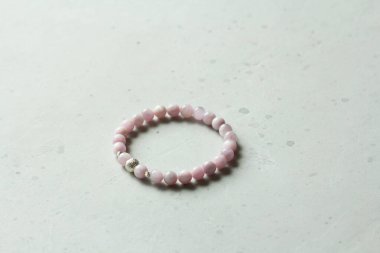 Kunzite bileziği. Bileklik, eldeki taşlardan yapılmış doğal bir kunzite taşından. Doğal taşlardan yapılmış bilezik. El yapımı mücevherler. Hafif modern arkaplanda el yapımı bilezikler.