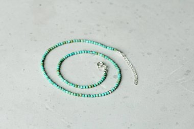 Turkuaz doğal taş boncuklardan yapılmış kısa kolye. Doğal taş turkuazından yapılmış taşlardan yapılmış bir kolye. Doğal taşlardan yapılmış bir kolye. Hafif modern arka planda el yapımı kolye..