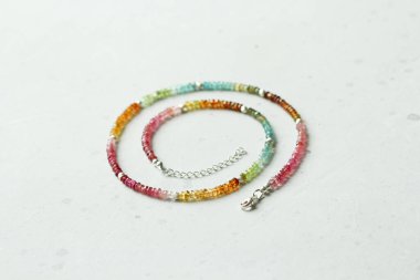 Gökkuşağı parlak renkli turmalinden yapılmış kısa kolye. Eldeki taşlardan yapılmış kolye, doğal taş turmalinidir. Doğal taşlardan yapılmış bir kolye. Hafif modern arka planda el yapımı kolye..