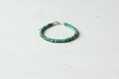 Turkuaz bilezik. Doğal Turkuaz taşından yapılma bilezik. Doğal taşlardan yapılmış bilezik. El yapımı mücevherler. Hafif modern arkaplanda el yapımı bilezikler.