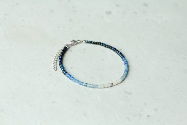 Safir bilezik. Bilezik, eldeki taşlardan yapılmış doğal taştan bir Safir. Doğal taşlardan yapılmış bilezik. El yapımı mücevherler. Hafif modern arkaplanda el yapımı bilezikler.