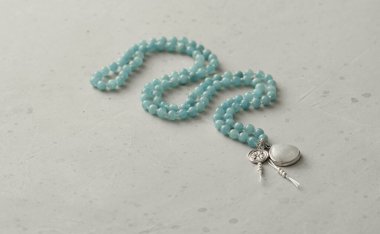 Doğal taşlardan toplanan 108 boncuklu tespih hafif modern arka planda yatar. Yazarın doğal taşlardan mücevherleri, Budizm, matra, dua, taşlardan tespih duası, güzellik. Uzun boncuklar.