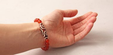 Cornelian Dzi boncuk bileziği. Doğal taş Cornelian taşlarından yapılmış bilezik. Doğal taşlardan yapılmış bilezik. El yapımı mücevherler. Hafif modern arkaplanda el yapımı bilezikler.