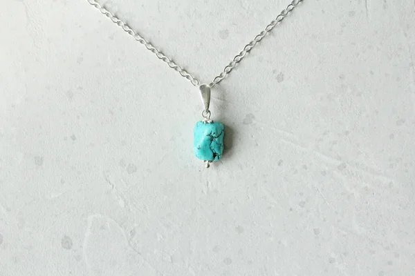 A pendant made of natural stone Turquoise silver chain. Author\'s jewelry from natural stones. Designer jewelry. On a light modern background. Natural minerals. Nugget.