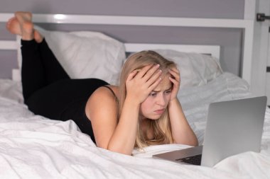 Dizüstü bilgisayarlı, beyaz çarşaflı güzel, bitkin bir sarışın. Tecritteki güzel insanlar