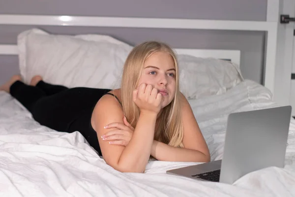 beautiful flirty blonde with laptop on bed with white sheets. pretty people at isolation