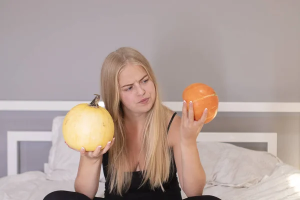 Beautiful blonde with two pumpkins in white bedroom. halloween concept — Stock Photo, Image