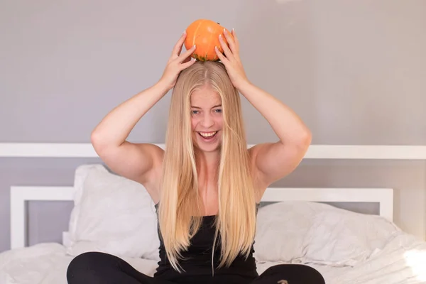 Mooie blonde met pompoen in witte slaapkamer. halloween concept — Stockfoto