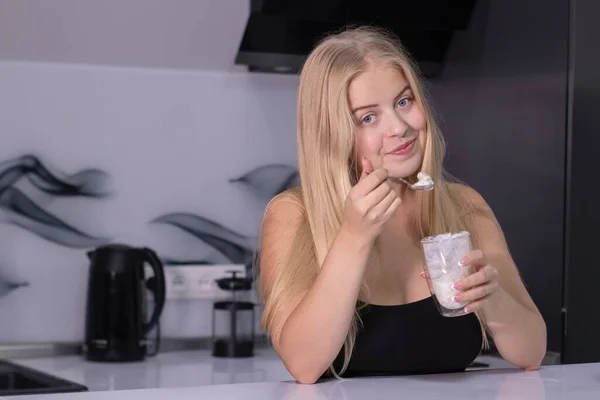 Atractiva rubia comiendo hojuelas con leche en cocina gris. concepto de desayuno saludable — Foto de Stock