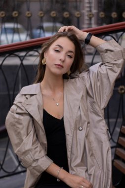 şık trençkotlu ve bankta oturan siyah elbiseli çekici, zayıf, genç bir esmer. Sonbahar, sarı yapraklar