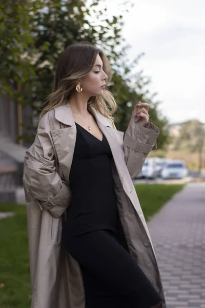 Aantrekkelijk slank jong brunette in modieuze trench jas en zwart jurk — Stockfoto
