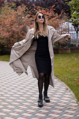 Havalı siperlerde, siyah elbiseli ve parkta güneş gözlüklü çekici, zayıf, genç bir esmer. Sonbahar, sarı yapraklar