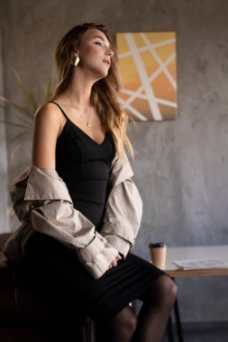 Gri çatı katında deri koltukta trençkotlu çekici, zayıf esmer. şehir yaşam tarzı kavramı