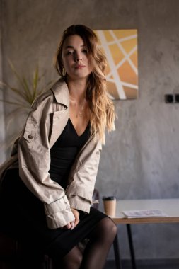 Gri çatı katında deri koltukta trençkotlu çekici, zayıf esmer. şehir yaşam tarzı kavramı