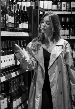 Şarapçıda rafların arasında şarap içen çekici bir kadın. siyah beyaz fotoğraf. yumuşak odak