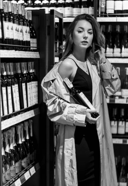 Atractiva mujer sexy en una tienda de vinos entre estantes con vino. foto en blanco y negro. enfoque suave —  Fotos de Stock