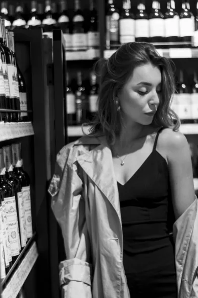Sexy attrayant femme dans un magasin de vin parmi les étagères avec du vin. photo en noir et blanc. foyer doux — Photo