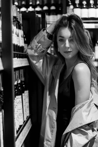 Atractiva mujer sexy en una tienda de vinos entre estantes con vino. foto en blanco y negro. enfoque suave —  Fotos de Stock