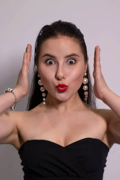 Retrato emocional de morena atraente em top preto com brincos de pérola branca em fundo branco — Fotografia de Stock