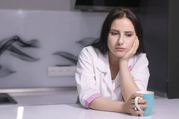Mavi fincanlı, beyaz ve pembe tıp önlüklü çekici esmer hemşire. İşten sonra yorgunum. Sağlık hizmeti, koronavirüs