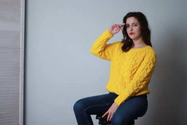 Kotlu ve sarı örülü süveterli çekici bir esmer. Stüdyo çekimi