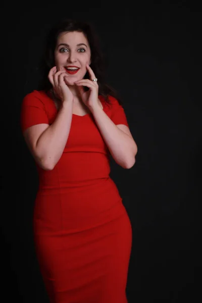 Sexig attraktiv brunett i röd smal klänning isolerad på svart bakgrund. Studioinspelning. emotionell skådespelerska. — Stockfoto
