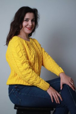 Kotlu ve sarı örülü süveterli çekici bir esmer. Stüdyo çekimi