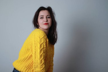 Kotlu ve sarı örülü süveterli çekici bir esmer. Stüdyo çekimi