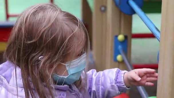 운동장에 있는 의학적 푸른 마스크를 쓴 귀여운 금발 소녀. 19 개 지방 자치체를 관할 한다. 고립 된 아이들. FullHD 영상. — 비디오