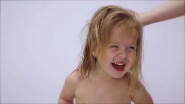 Saç kurutma işlemi. Anneler saçlarını güzel, mutlu, sarışın bir kızın saç kurutma makinesiyle kurutur. Saç bakımı. Ebeveynlik. Tam HD görüntüler