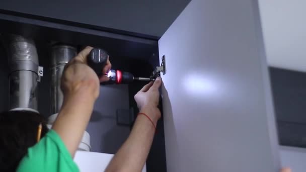 Processo de renovação de apartamentos. fettler broca pregos com uma chave de fenda elétrica em dobradiças de porta na fachada. Homens irreconhecíveis. remodelação, fazer reparos. Imagens FullHD — Vídeo de Stock