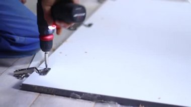 Daire yenileme işlemi. Fettler ön cepheye elektrikli tornavidayla çivi çakıyor. Tanımlanamayan adamlar. Tadilat, onarım. Tam HD görüntüler