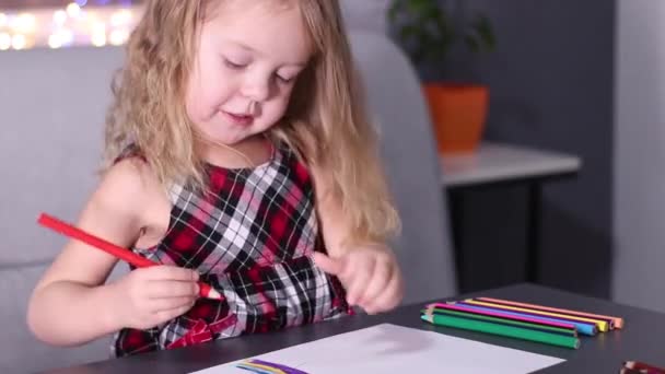 Γοητευτικό μικρό ξανθό κορίτσι σε κόκκινο καρό φόρεμα ζωγραφική με πολύχρωμα μολύβια. παιδική ηλικία, νήπιο, κόρη. FullHD πλάνα — Αρχείο Βίντεο