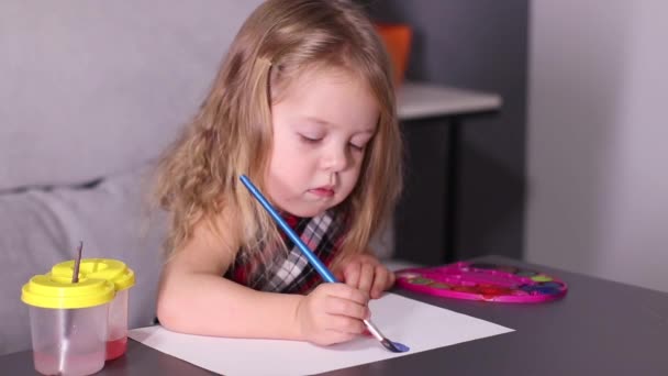 赤いチェッカードレスの魅力的な小さなブロンドの女の子カラフルな絵具で絵を描く。子供の頃、芸術、塗料。フルHD映像 — ストック動画