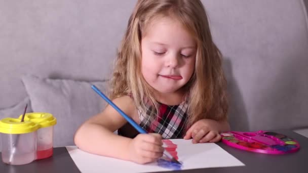 Charmante petite fille blonde en robe à carreaux rouges, peinture avec des peintures colorées. enfance, art, peinture. Vidéos en Full HD — Video