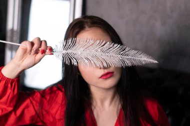 Büyük beyaz tüylü, kırmızı bluzlu çekici esmer kadın portresi. Sevgililer Günü, romantizm, romantik. Boşluğu kopyala.