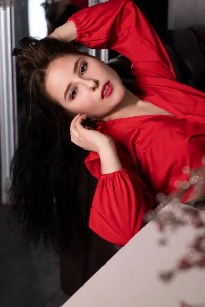 漂亮的黑发女人的画像 穿着红色衬衫躺在皮革沙发上 圣瓦伦丁 复制空间 — 图库照片