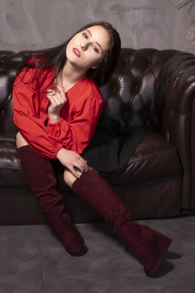 Портрет Привлекательной Брюнетки Красной Блузке Черной Юбке Сидящей Кожаном Диване — стоковое фото