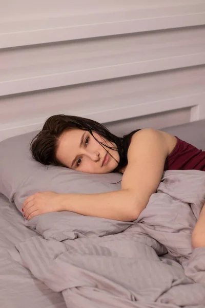 Üzgün Uykulu Esmer Kız Bordo Bluzlu Gri Çarşafların Altında Yatakta — Stok fotoğraf
