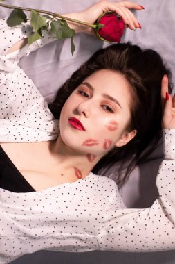 Seksi esmer kadın, öpücükler, yüzünde ve boynunda ruj izleri, kırmızı gül. Kız arkadaş, randevu, ilişki. Boşluğu kopyala