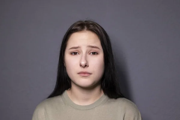灰色の壁の背景に沼の色のTシャツの魅力的な悲しいブルネットの女性の肖像画 女優の演技感情 コピースペース — ストック写真