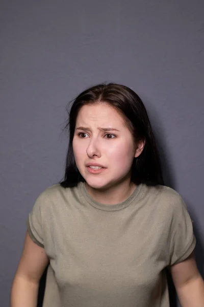 Gri Arka Planda Bataklık Rengi Tişörtlü Çekici Korkmuş Esmer Kadın — Stok fotoğraf