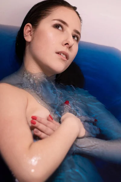 迷人的黑发女人半裸着身披蓝色液体的肖像 在有彩色水的浴缸里 溺水的女孩复制空间 — 图库照片