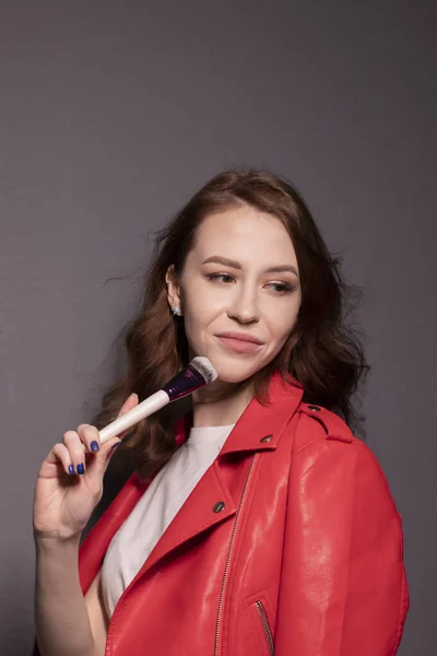 Kırmızı Deri Ceketli Çekici Esmer Kadın Makyaj Fırçaları Gri Duvar — Stok fotoğraf